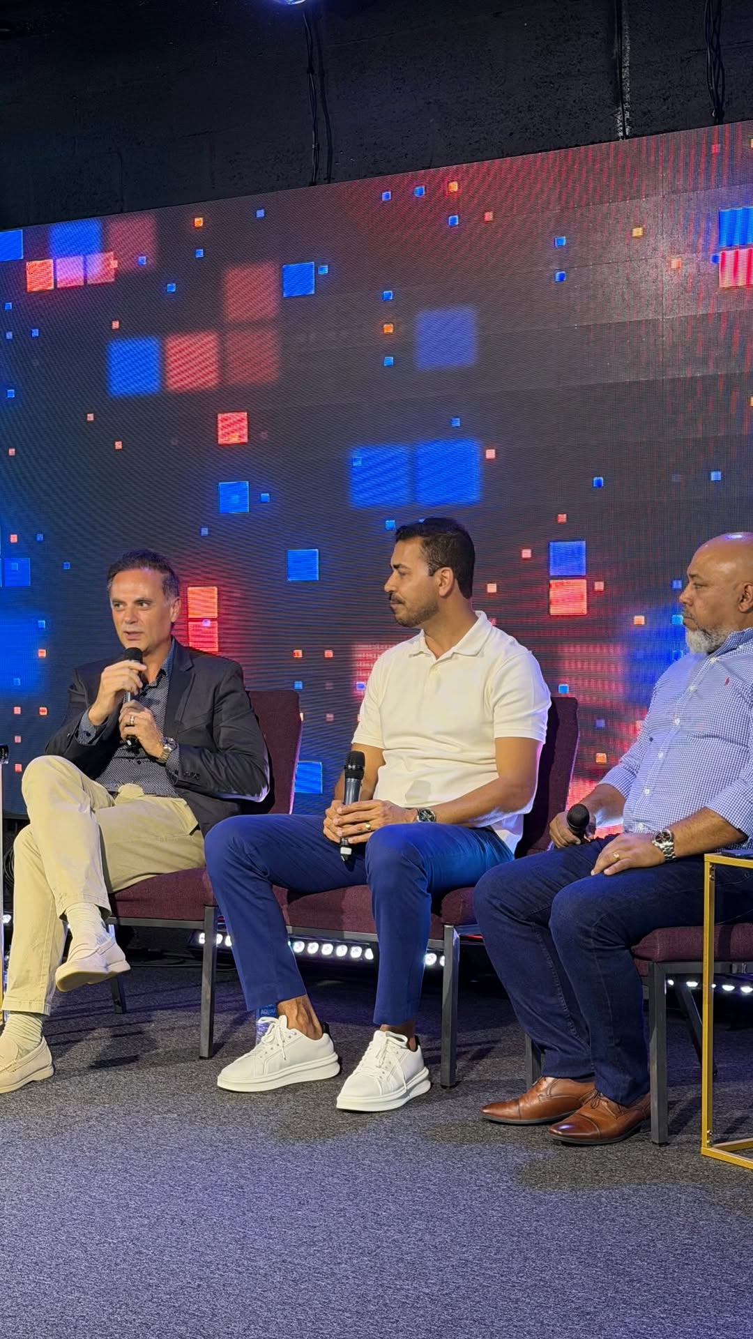 Luciano Stein de blazer falando em um painel durante um evento